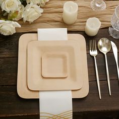 a place setting with flowers and candles on a wooden table cloth, napkins and silverware