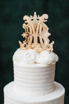 a white wedding cake with gold monogram on top