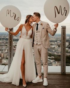 a bride and groom kissing while holding balloons with the word mr and mrs written on them