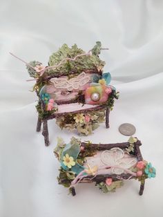 there are two miniature furnitures made out of flowers and leaves on the table next to a coin