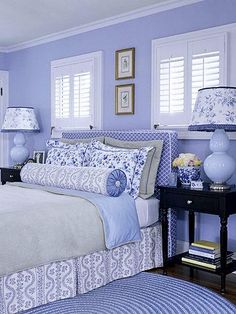 a bedroom with blue and white bedding and two lamps on either side of the bed