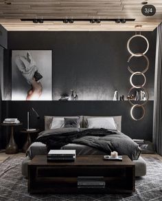 a modern bedroom with black walls and grey bedding, artwork above the headboard