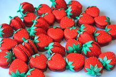 a pile of red and green strawberries sitting on top of a white table next to each other