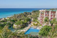 an aerial view of the resort and its surrounding pool area with palm trees, blue water and ocean in the background