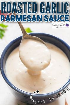 a spoon full of homemade roasted garlic parmesan sauce in a small blue bowl