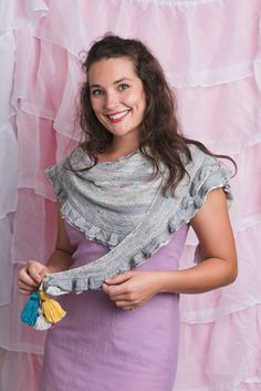 a woman in a purple dress is smiling and holding a tasseled shawl