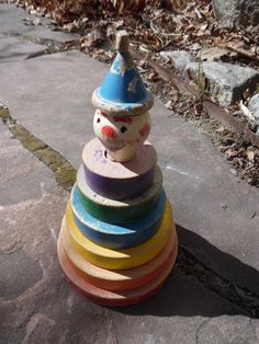 a stack of colorful wooden toys sitting on top of a stone floor next to leaves