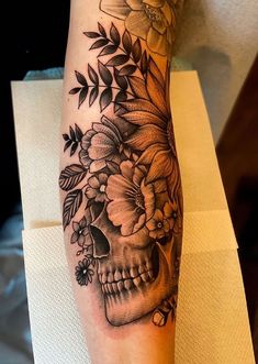 a woman's leg with a skull and flowers tattoo on the side of her arm