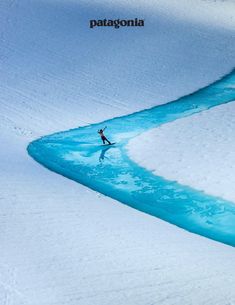 a man riding skis down the side of a snow covered slope next to a river