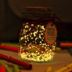 a jar filled with lots of colorful crayons next to some writing utensils