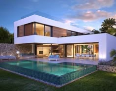 a large white house with a swimming pool in front of it at night time, surrounded by lush green grass and trees