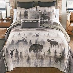 a bed covered in a comforter with deer and trees on the cover, along with two pillows