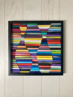 an art piece made out of colored pencils in a black frame on a white wall