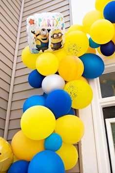 a birthday party decoration with balloons and minion figures on the front of a house