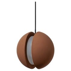 a brown and white object hanging from a black cord on a white background with the light reflecting off of it's sphere