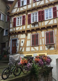 a bike parked in front of a building with red shutters on it's windows