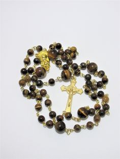 "This Tiger's eye Catholic rosary is made with Grade a gemstones. The hand turned links are gold plated as is the connector. The golden cross is from Italy. The rosary measures 26\" in the body and has a 5\" cross drop. This rosary will be slipped into a velvet bag and shipped in a bubble mailer." Gold Rosary With Gemstone Beads Gift, Gold Rosary Bracelet With Cross And 8mm Beads, Gold Spiritual Rosary With Gemstone Beads, Gold Spiritual Rosary Bracelet With Polished Beads, Gold Rosary Bracelet With Natural Stones And Round Beads, Gold Gemstone Beads Rosary, Spiritual Gold Rosary With 8mm Beads, Gold Spiritual Rosary With Round Beads, Gold Spiritual Rosary With Cross