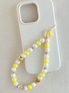 a cell phone case with a yellow and white beaded necklace on it's side