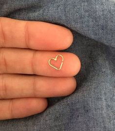 a person's hand with a tiny heart on their finger and a small gold ring in the middle