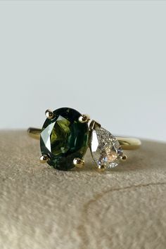 two green and white diamond rings sitting on top of a cushioned surface in front of a light gray background