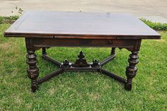 an old wooden table sitting on top of green grass in the middle of a yard