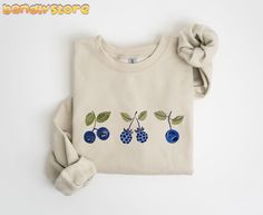 Get ready to cozy up in this cute Vintage Blue Berries Sweatshirt! Perfect for summer days spent in the garden or for simply lounging around. This adorable sweatshirt features three blue berries in a vintage cottagecore design that will surely become your favorite piece of clothing. Whether you're a gardener or simply a berry lover, this Blueberry Sweatshirt makes a perfect addition to your wardrobe. Treat yourself or surprise a loved one with this unique and sweet gift for her 💙🫐 GILDAN 18000 Blueberry Sweater, Patch Work Clothes, Cottagecore Design, Blue Berries, Patchwork Clothes, Buy Clothes Online, Vintage Cottagecore, Gardening Shirts, Sweet Gifts