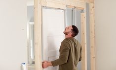 a man standing in front of a white door and looking up at the ceiling frame