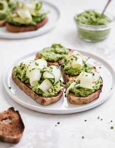 two white plates topped with sandwiches covered in guacamole