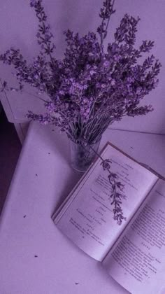 an open book sitting on top of a table next to a vase filled with flowers