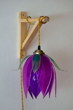 a purple flower hanging from a hook on a wall