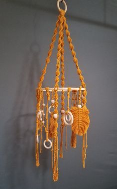 an orange macrame hanging from a hook on a wall with other macrame beads