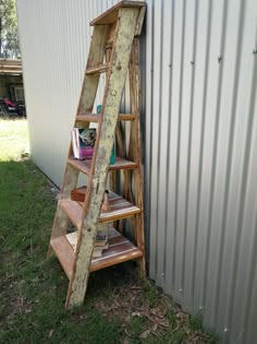 an old ladder leaning against the side of a building with bookshelves on it