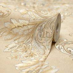 a roll of metallic foiled paper on top of a white table cloth with gold floral designs