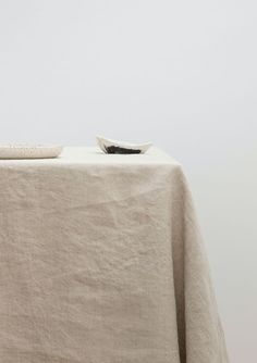 a table with a white cloth on it and a black bowl sitting on top of it