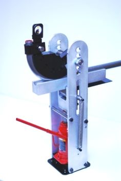 a machine that is sitting on top of a white surface with red tools in it