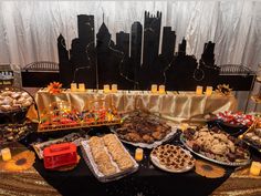 an assortment of food on a table in front of a cityscape with candles