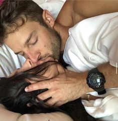 a man laying in bed with his head on the woman's shoulder while she sleeps next to him