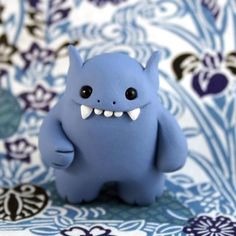 a small blue monster figurine sitting on top of a flowered table cloth