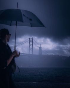 a woman holding an umbrella in front of the golden gate bridge