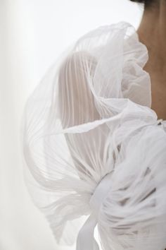 a woman wearing a white dress with ruffles on it