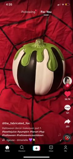 a green and white vase sitting on top of a red bed cover covered in black and white stripes