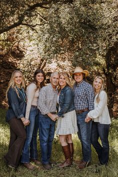 a group of people standing next to each other in front of some trees and grass