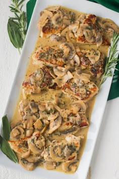 a white plate topped with meat covered in mushroom sauce and garnished with herbs