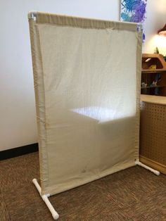 a room with a large white sheet on the floor next to a shelf and lamp