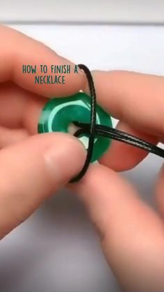 a person is holding a green ring with black cord in their left hand and the words how to finish a necklace on it