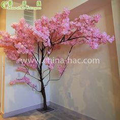 a tree with pink flowers in the corner of a room