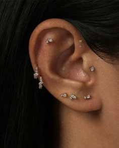 a close up of a woman's ear with several small diamond studs on it