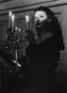 a woman standing in front of a chandelier with candles