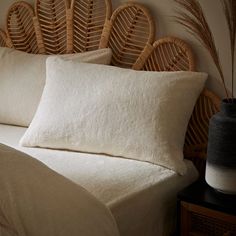 a bed with white sheets and pillows on top of it next to a black vase