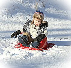 a young boy riding a sled down a snow covered slope